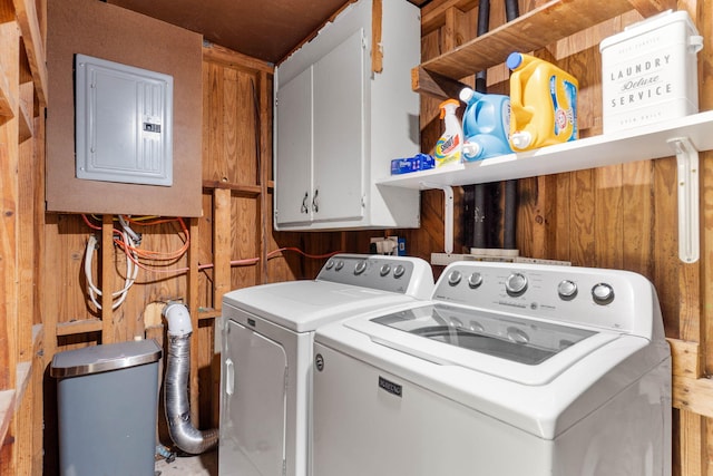 washroom featuring washer and dryer, electric panel, cabinet space, and wooden walls