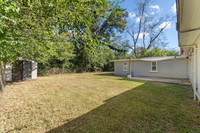 view of yard with a shed, fence, a patio, and an outdoor structure