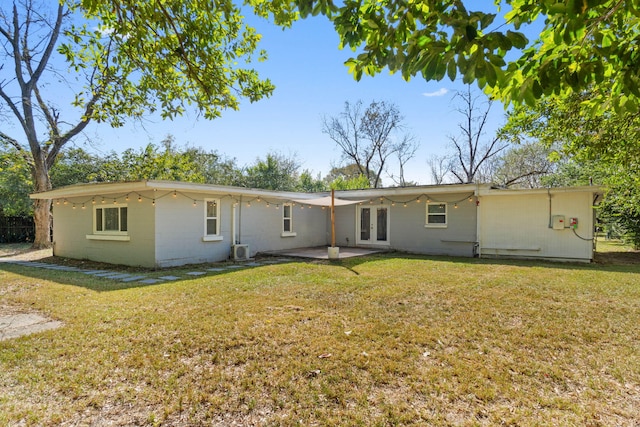 rear view of house with french doors, a lawn, a patio area, and concrete block siding