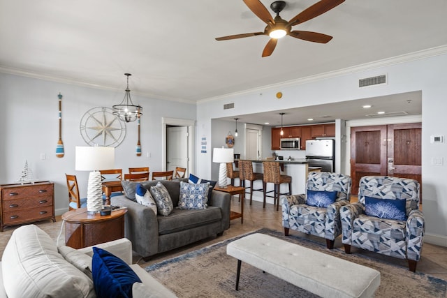 living room with baseboards, ornamental molding, ceiling fan with notable chandelier, and visible vents