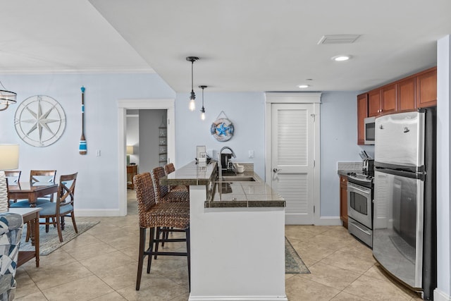 kitchen with appliances with stainless steel finishes, a breakfast bar, a sink, a peninsula, and light tile patterned floors