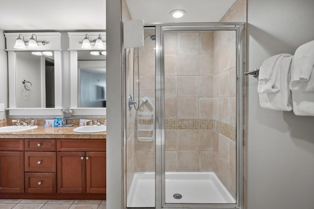 bathroom featuring double vanity, a sink, a stall shower, and tile patterned flooring