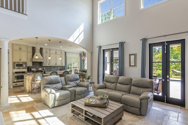 living area featuring ornate columns, stone tile floors, arched walkways, and a wealth of natural light