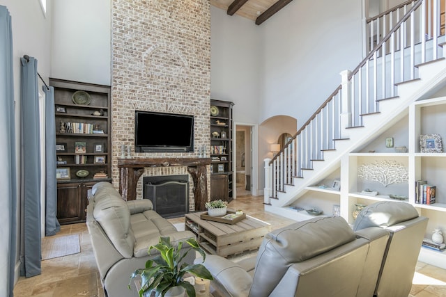 living area featuring arched walkways, built in shelves, a high ceiling, a fireplace, and stairway