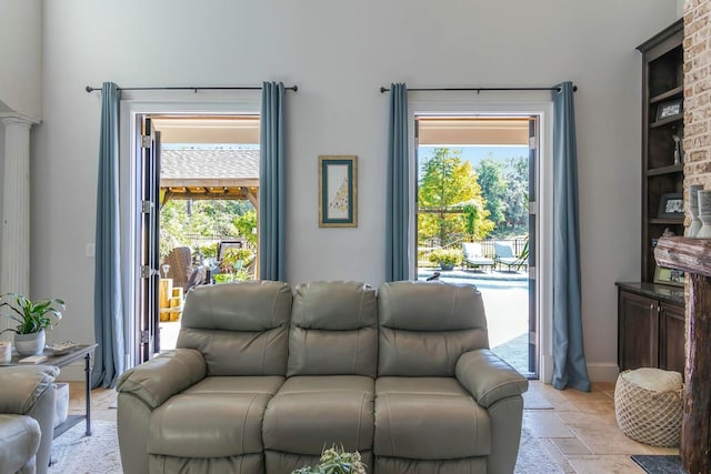 living room featuring a healthy amount of sunlight, stone tile floors, and decorative columns