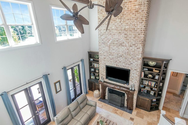 living room with ceiling fan, a fireplace, and a high ceiling