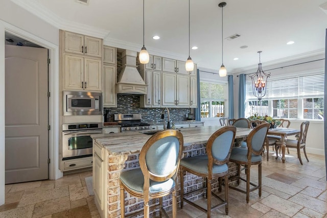 kitchen featuring visible vents, stainless steel appliances, stone tile flooring, premium range hood, and a sink