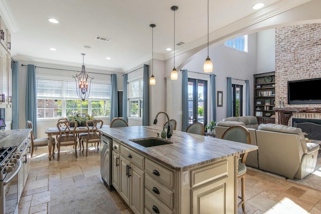 kitchen featuring stone tile floors, open floor plan, cream cabinets, stainless steel appliances, and a sink