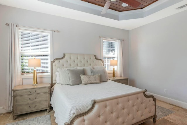 bedroom with a tray ceiling, a ceiling fan, visible vents, and baseboards