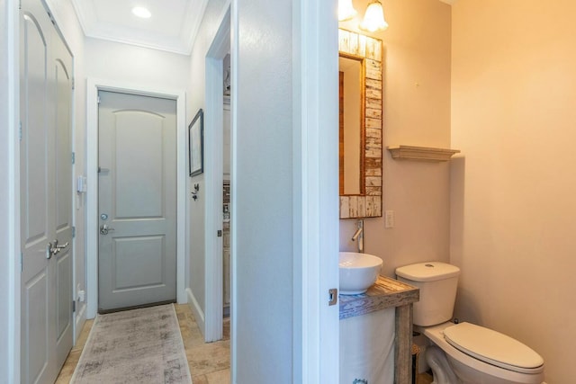 bathroom with toilet, ornamental molding, and vanity