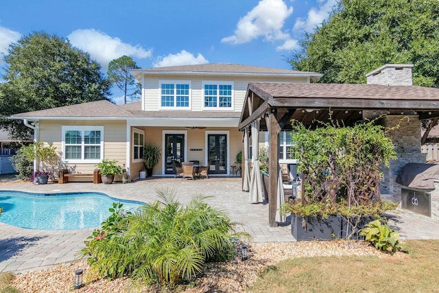 back of house with french doors, a patio area, an outdoor pool, and a chimney