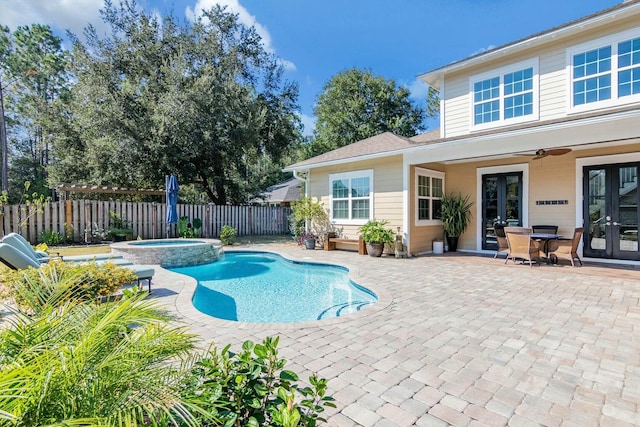 view of swimming pool with french doors, a pool with connected hot tub, a patio area, ceiling fan, and a fenced backyard