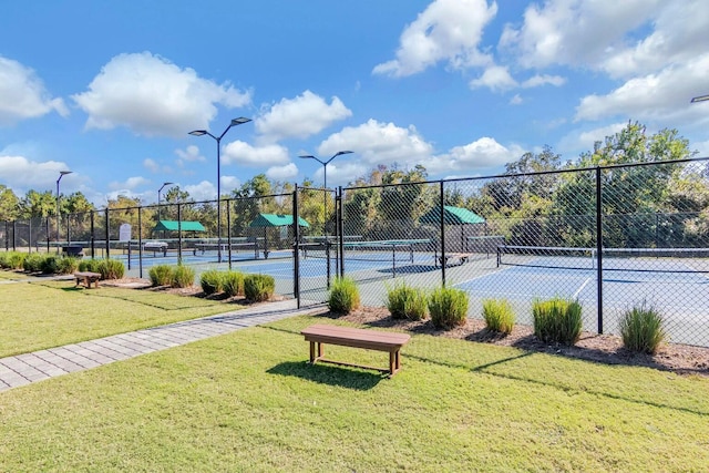 view of sport court with fence and a lawn