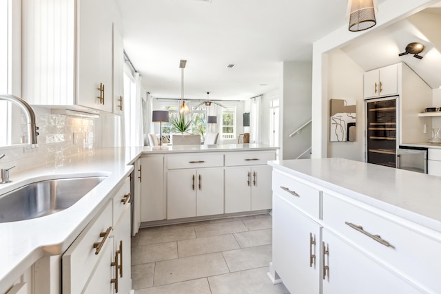 kitchen featuring light tile patterned flooring, a sink, white cabinetry, light countertops, and backsplash