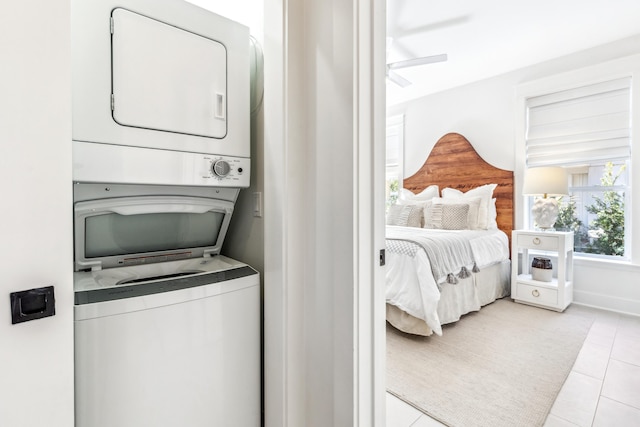 laundry area featuring stacked washer and dryer, laundry area, light tile patterned flooring, and a ceiling fan