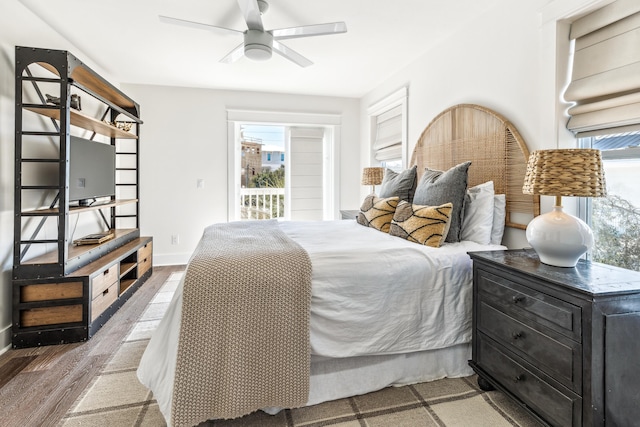 bedroom featuring multiple windows, wood finished floors, a ceiling fan, and baseboards