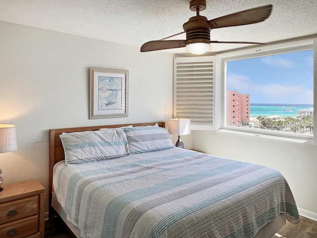 bedroom with ceiling fan, a textured ceiling, and wood finished floors