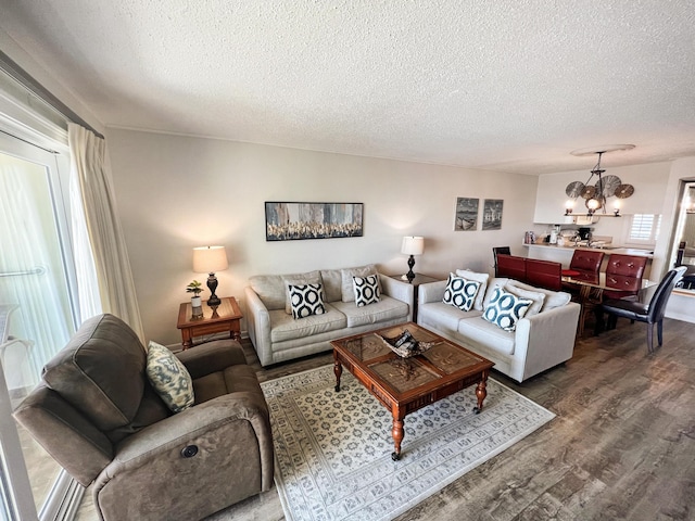 living area with an inviting chandelier, a textured ceiling, and wood finished floors