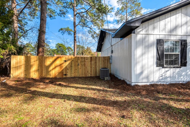 view of side of home with central AC unit, board and batten siding, and fence