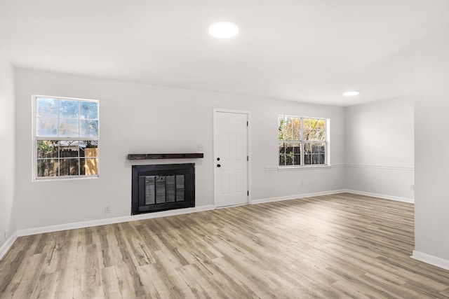 unfurnished living room with a glass covered fireplace, recessed lighting, baseboards, and wood finished floors