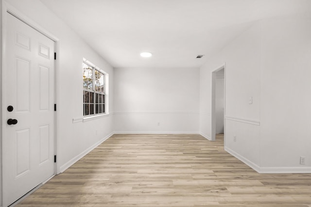 empty room with light wood finished floors, baseboards, and visible vents