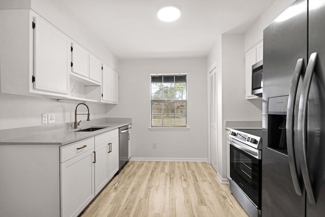 kitchen featuring light countertops, appliances with stainless steel finishes, light wood-style floors, white cabinets, and a sink