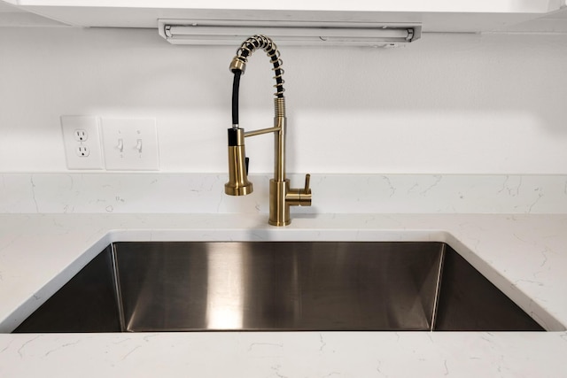 details featuring light stone counters and a sink