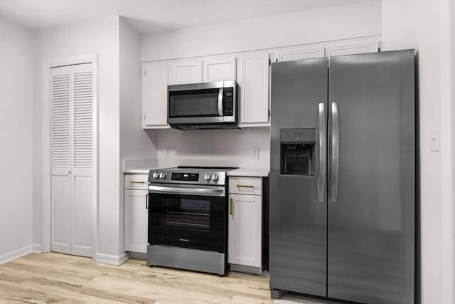 kitchen with appliances with stainless steel finishes, light wood-type flooring, light countertops, and white cabinetry