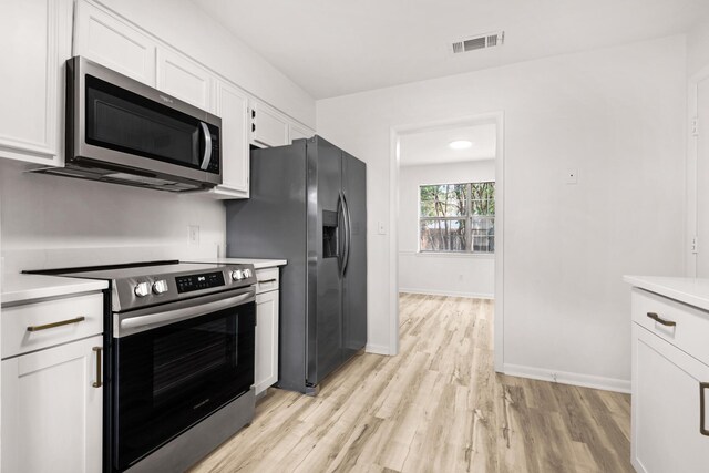 kitchen with light wood finished floors, stainless steel appliances, light countertops, visible vents, and white cabinetry