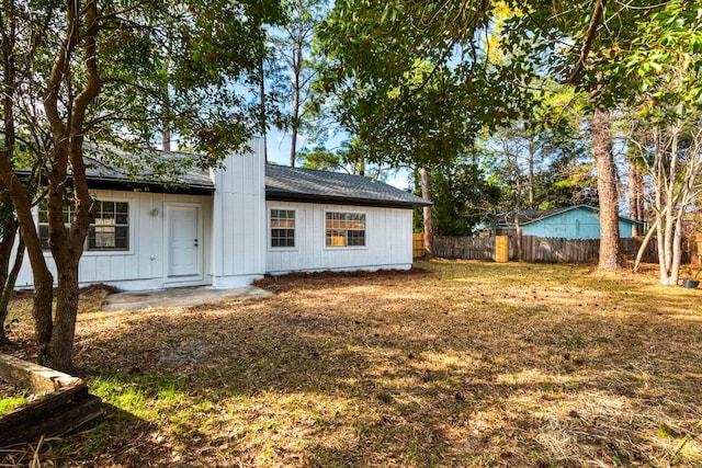 back of house with a shingled roof and fence