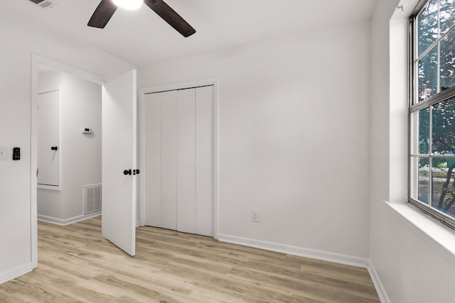 unfurnished bedroom with visible vents, a closet, light wood-style flooring, and baseboards