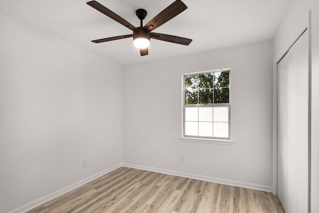 empty room featuring baseboards, a ceiling fan, and light wood-style floors