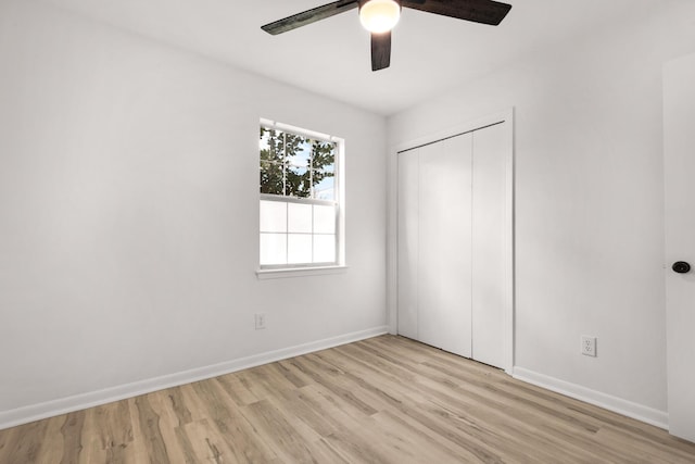 unfurnished bedroom featuring light wood finished floors, a ceiling fan, baseboards, and a closet