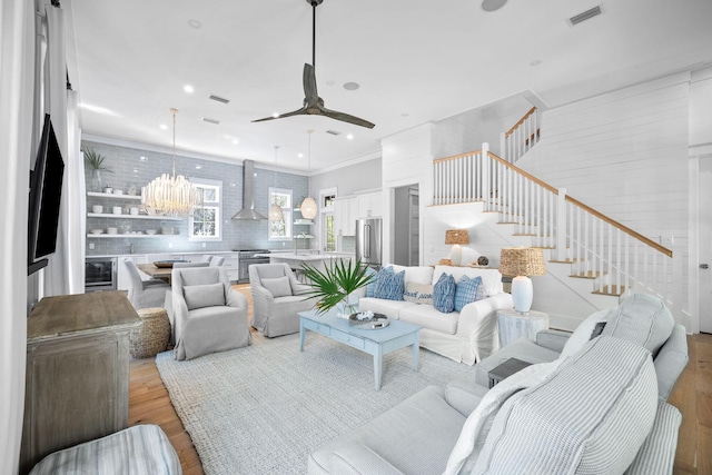 living area featuring ceiling fan, wine cooler, visible vents, stairs, and light wood-type flooring