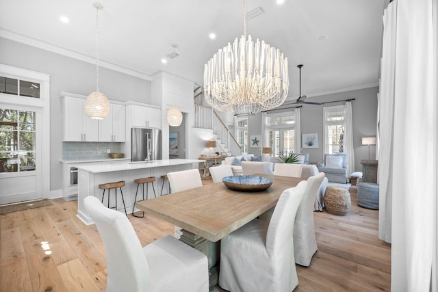 dining room featuring a chandelier, visible vents, stairs, light wood-type flooring, and crown molding