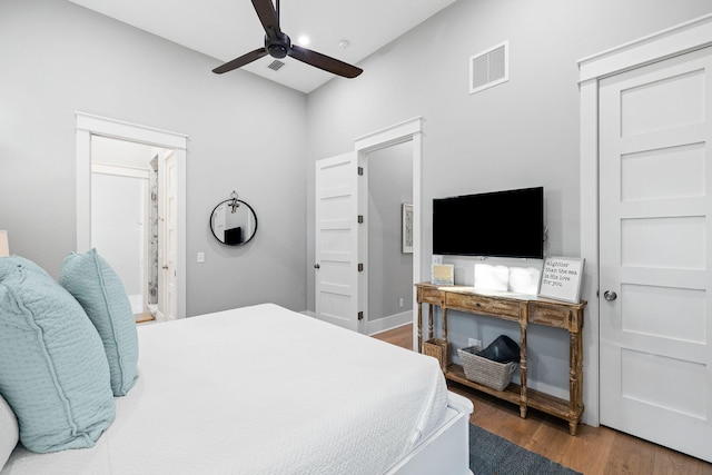 bedroom featuring ensuite bath, ceiling fan, visible vents, and wood finished floors