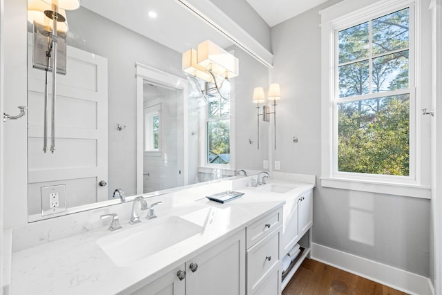 bathroom featuring double vanity, baseboards, a sink, and wood finished floors