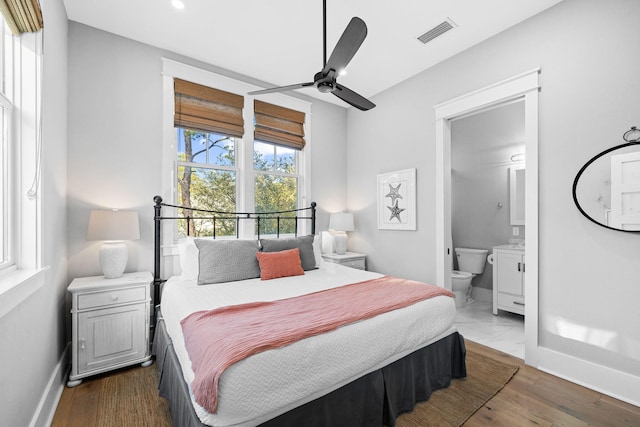 bedroom with baseboards, visible vents, wood finished floors, and ensuite bathroom