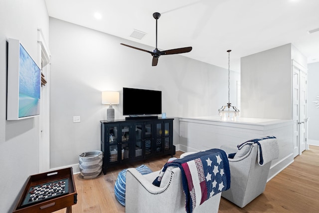 living area with a ceiling fan, baseboards, visible vents, and wood finished floors