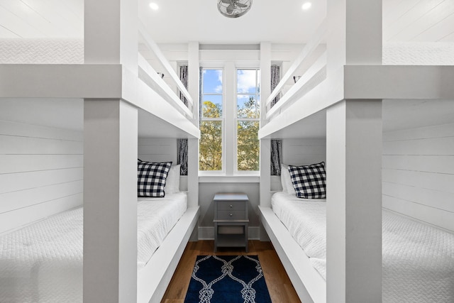 bedroom with wooden walls, wood finished floors, and recessed lighting