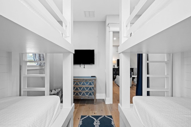 bedroom featuring wood finished floors, visible vents, and baseboards