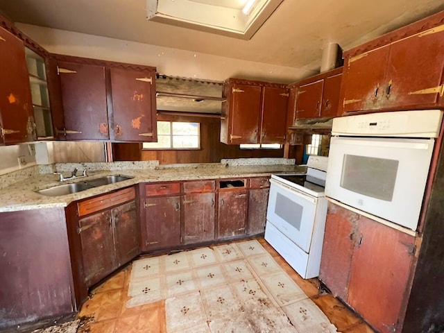 kitchen with light stone counters, white appliances, a sink, and light floors