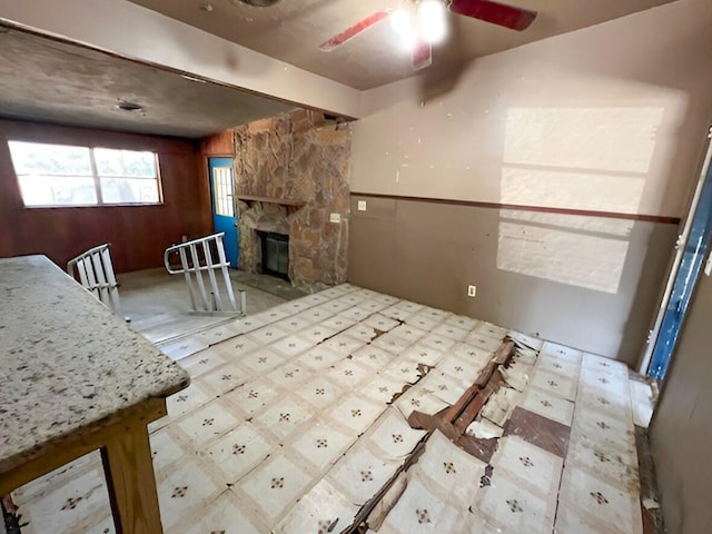 interior space featuring ceiling fan, a stone fireplace, and tile patterned floors