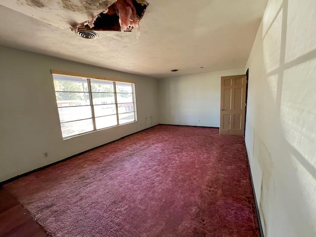 empty room featuring carpet floors, baseboards, and visible vents