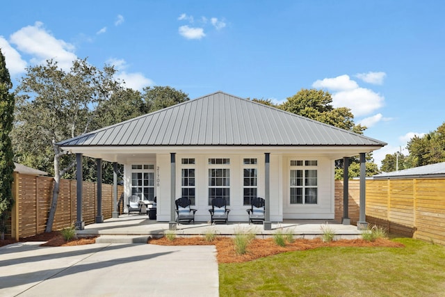 rear view of house with metal roof, fence, and a porch