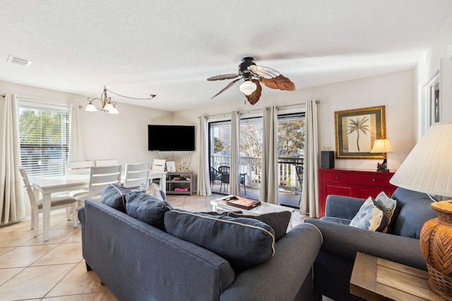 living room with light tile patterned floors, visible vents, a textured ceiling, and ceiling fan with notable chandelier