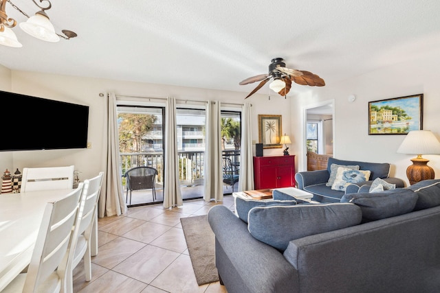 living area featuring a textured ceiling, light tile patterned floors, and ceiling fan