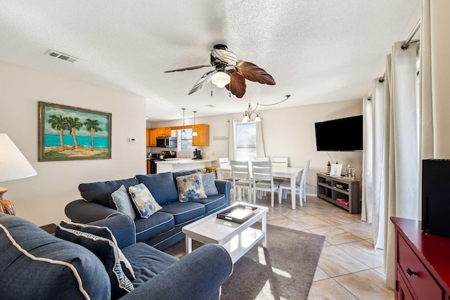 living room with light tile patterned floors, visible vents, a textured ceiling, and ceiling fan