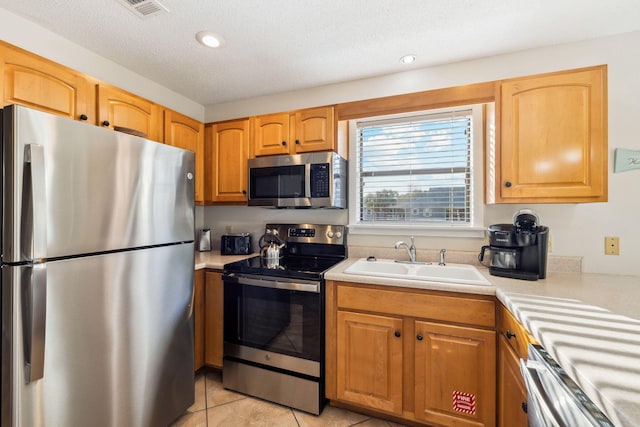 kitchen with visible vents, light tile patterned flooring, a sink, light countertops, and appliances with stainless steel finishes