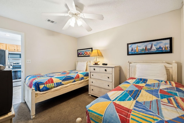 bedroom featuring carpet flooring, a ceiling fan, visible vents, and a textured ceiling